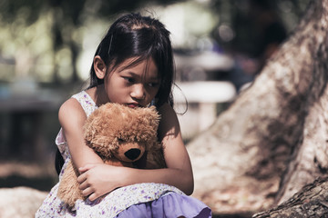 Adorable sad girl with teddy bear in park, Little girl is hugging a teddy bear.Upset child.
