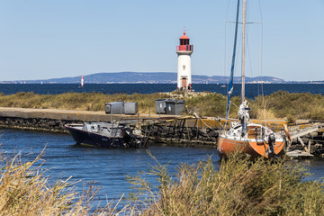 Boats in the Canal du Midi, with the Les Onglous lighthouse in the background. A World Heritage Site. Agde, France