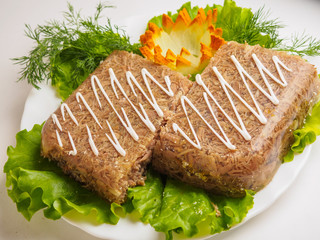 Russian aspic jelly with greens on a white plate