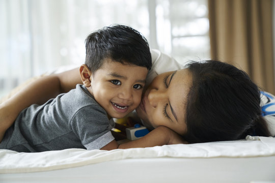  Mother kissing her son on the bed