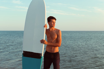 Handsome surfer holding his surfboard