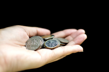 Pile of Thai coins on left Asian woman hand on black background, saving money concept, Clipping path of hand