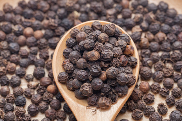 Whole Black Pepper On Wooden Spoon