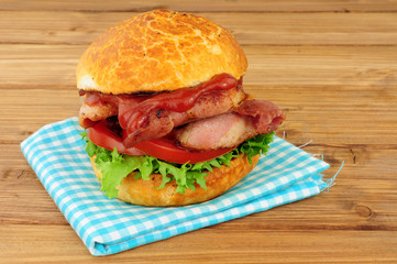 Bacon lettuce and tomato crusty sandwich roll on a wood background