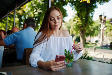 Portrait of an attractive young businesswoman with a mojito cocktail texting a message on her smatphone.