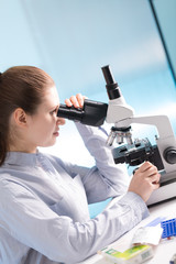 Doctor woman working  a microscope. Female scientist looking through a microscope in lab. Student girl looking in a microscope, science laboratory concept