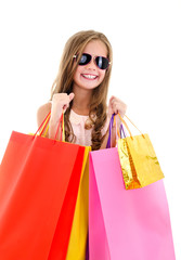 Adorable little girl child in sunglasses holding shopping colorful paper bags