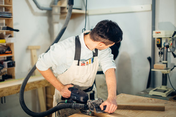 Carpenter planing timber in light workshop