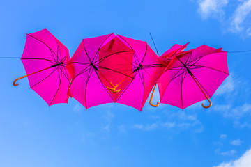 parasols roses suspendus, fond de ciel bleu 
