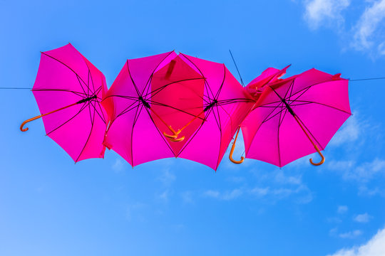 parasols roses suspendus, fond de ciel bleu 