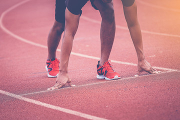close up of man runner starting in the track. Fit male fitness runner jogging in stadium