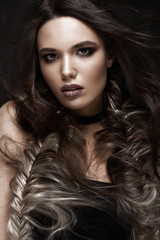 Brunette girl with a creative hairstyle braids and dark make-up. Beauty face. Photo taken in the studio.