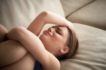 Stressed young lady lying on couch at home and crying. Unhappy woman suffering from nervous tension, emotional disorders, psychological problems, breakup. Frustrated female feeling lonely and offended