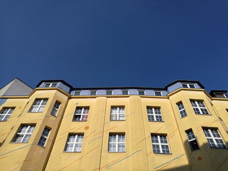 Sanierter Altbau in Beige und Naturfarben mit schönen großen Sprossenfenstern vor blauem Himmel...