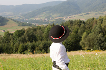 Child boy in traditional folk dress looking at mountain