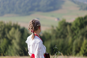 Child girl in traditional folk dress looking at mountain