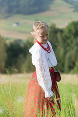 Young girl in traditioal Polish mountain dress stands on green meadow