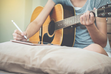 Fototapeta premium Female musicians play guitar and write songs using the tablet.This image is blurred and soft focus.