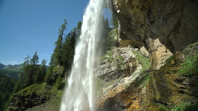 4k nature video waterfall over rocks in forest with blue sky, sunshine and audio

