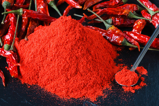 Cayenne red pepper powder in white bowl over wooden background