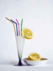 bere una limonata una limonata dentro ad un bicchiere a forma di calice, a lato un limone tagliato in due parti