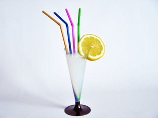 bere una limonata una limonata dentro ad un bicchiere a forma di calice, a lato un limone tagliato in due parti