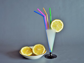 bere una limonata una limonata dentro ad un bicchiere a forma di calice, a lato un limone tagliato in due parti