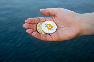 Bitcoins are in hand on the background of water