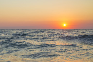 Fototapeta na wymiar Mare e cielo durante il tramonto in un tratto di costa tra Agropoli e Santa Maria di Castellabate. Il cielo è arancione e il mare mosso e pieno di onde. 