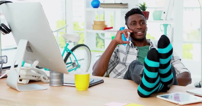 African American man executive talking on mobile phone while relaxing at his desk in office 