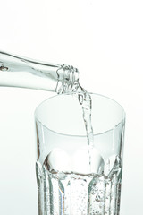 Pouring water from bottle into glass on white