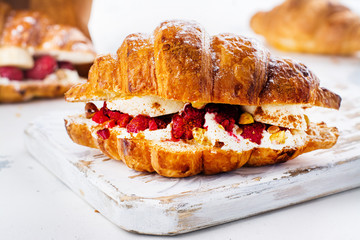 French croissants with cream cheese and raspberry, cinnamon and almond nuts. Copy space