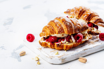 French croissants with cream cheese and raspberry, cinnamon and almond nuts. Copy space
