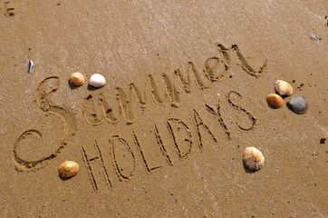 SUMMER HOLIDAYS hand-lettered in the sand with seashells