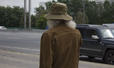 an old man in a hat with a beard looks on the way back