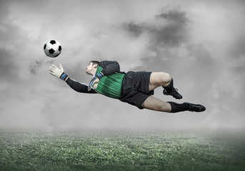 Football player with ball in action under sky with clouds