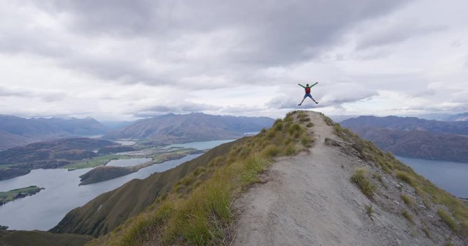 Hiker jumping of joy funny - man hiking in New Zealand. Roys Peak, South Island, New Zealand. SLOW MOTION.