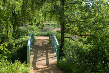 Beautiful summer garden bridge by a lake in the English countryside.