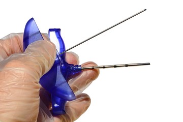 Bone marrow biopsy needle spliteed in two parts, tube and needle, held in left hand of a doctor in sterile latex glove, white background