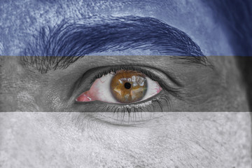 Human face and eye painted with flag of Estonia