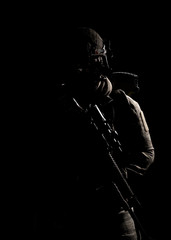 Soldier in military uniform with assault rifle on background of dark wall 25