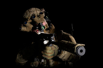 Soldier in military uniform with assault rifle aiming at target on background of dark wall 23