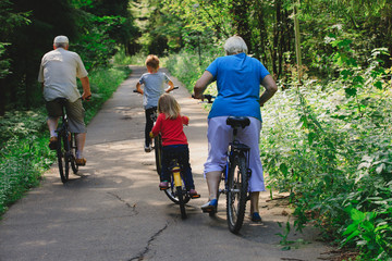Obraz premium active senior couple with kids riding bikes in nature
