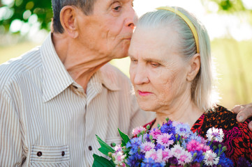 Two old people relax and hug each other in a park