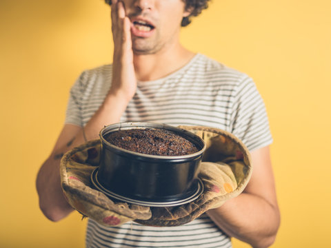 Upset young man with burnt cake