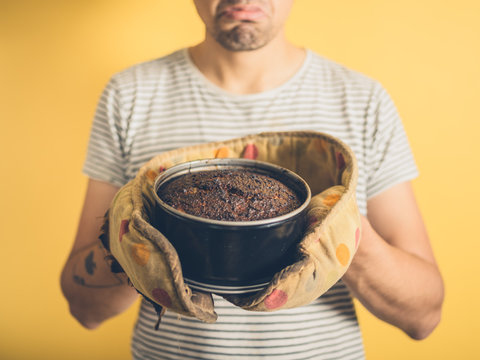 Upset young man with burnt cake