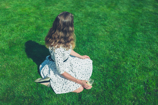 Woman in dress sitting on lawn in summer
