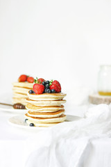 Pancakes with berries and honey on white background