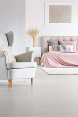 Fototapeta na wymiar Grey armchair in trendy bedroom