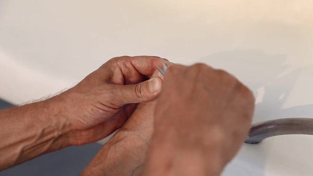 Adult caucasian man cutting long toenails on foot with scissors. Bathroom bath closeup toe nail cut